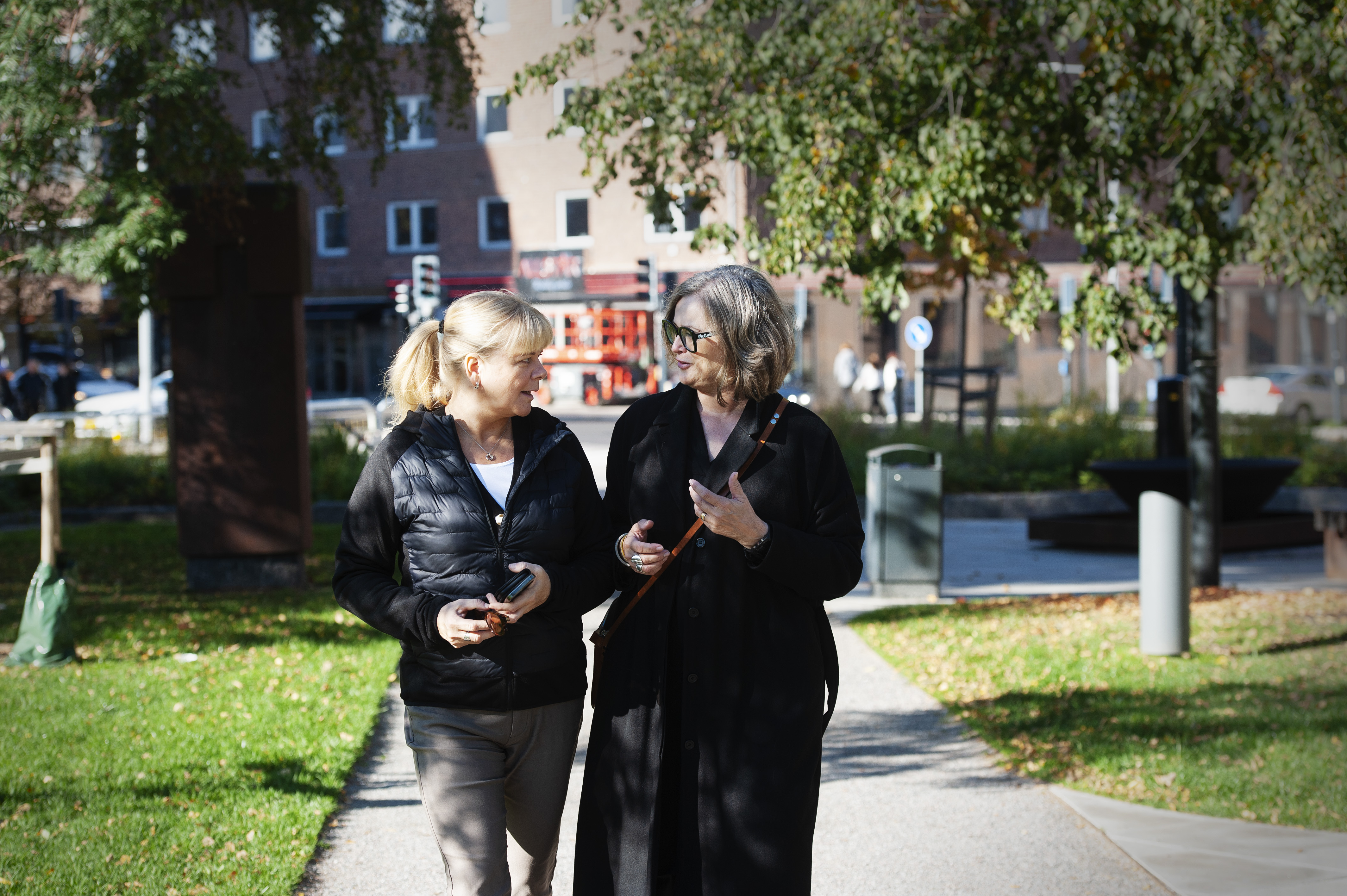 Upphandlaren Marie-Helen Gidlund på promenad med Sari Huczkowski i en höstig stadspark.