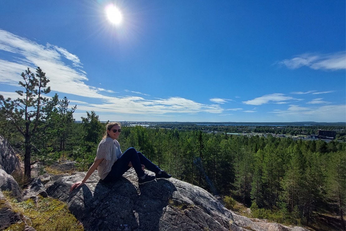 Rebecca Klaue sittandes på en sten med utsikt över Luleå