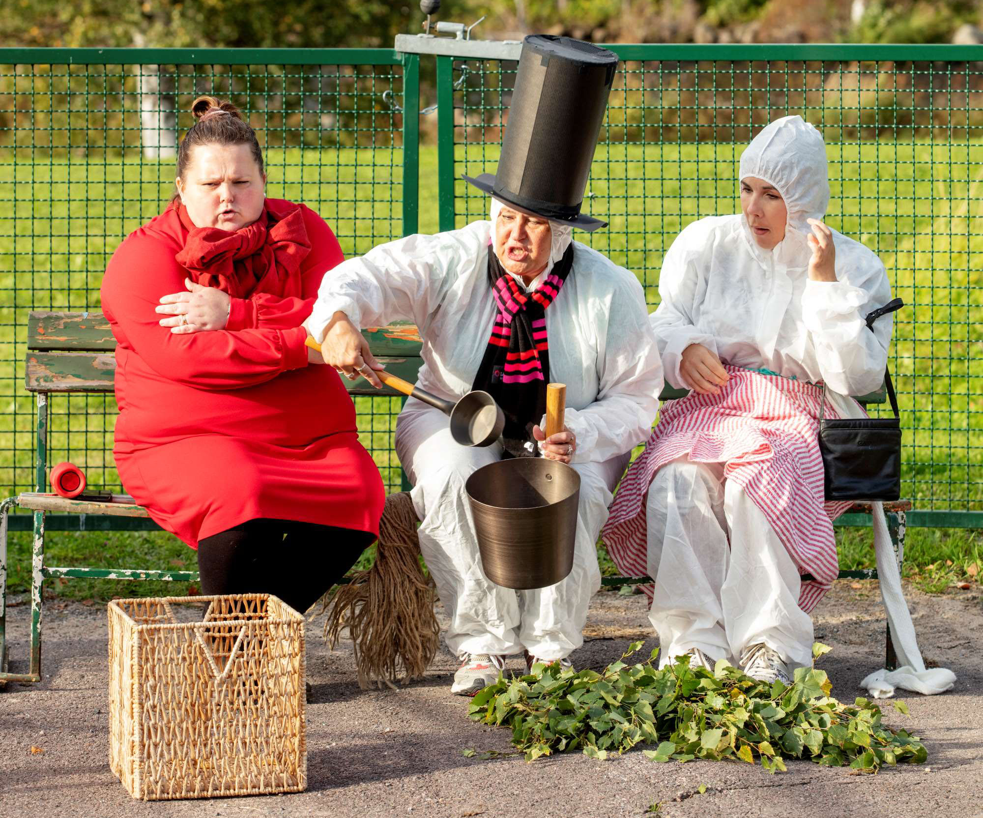 Bild från teaterföreställningen där muminpappan slänger på mer vatten på bastuaggregatet. Han är sitter tillsammans med Lilla My och Muminmamman.