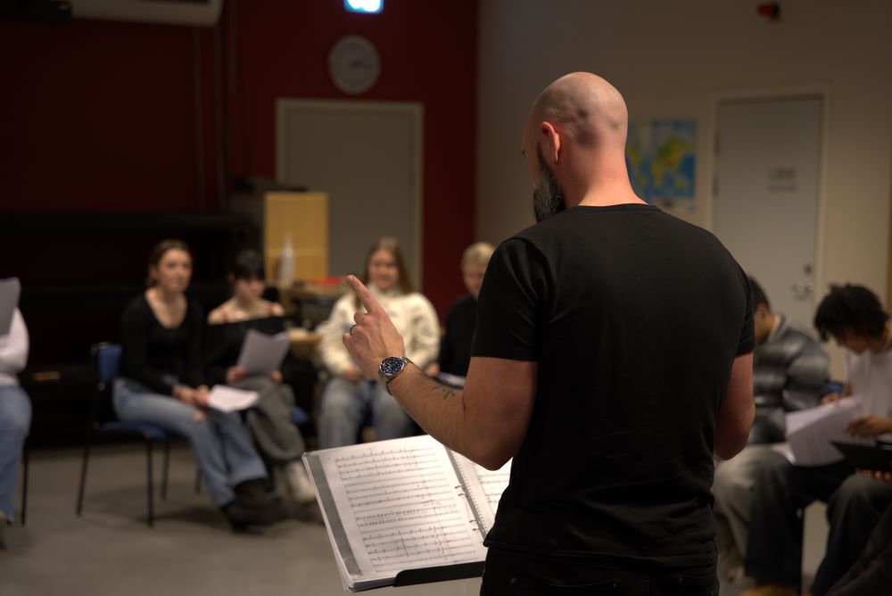 Per-Arne Petersson Ronander, som dirigerar Julkantaten, bakifrån. I bakgrunden syns elever lite suddigt.