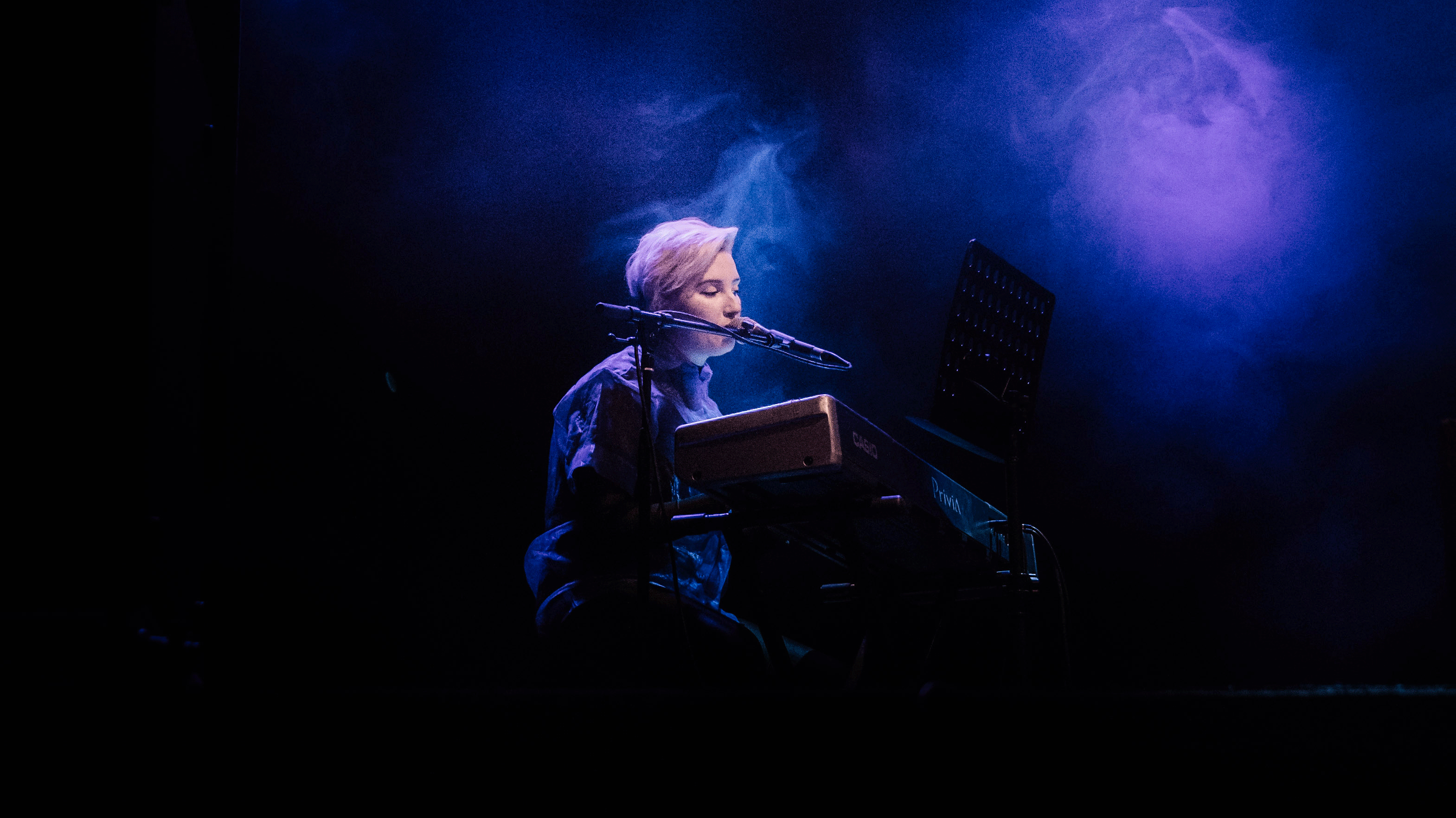 Woman singing on a dark stage.