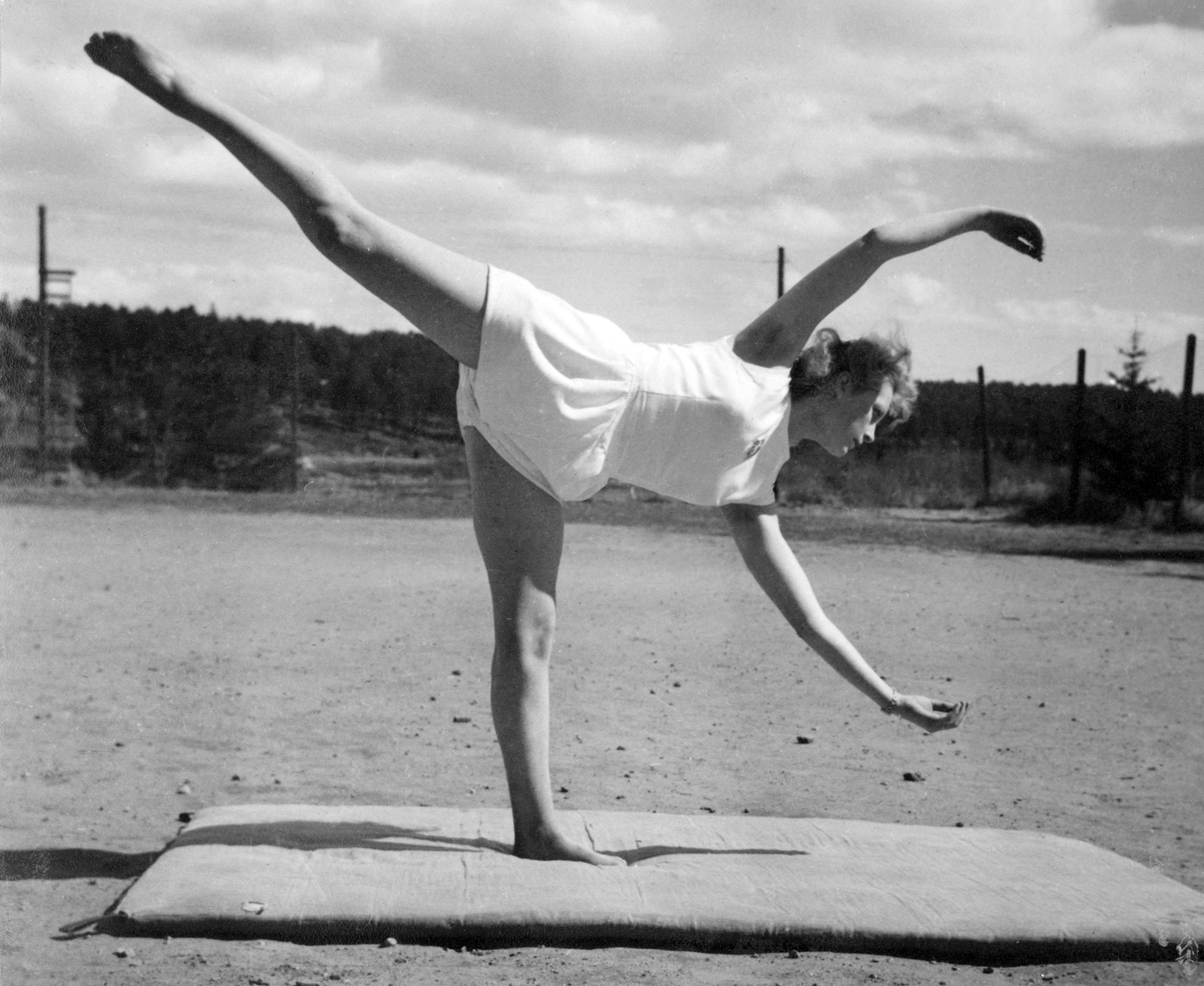 Kvinnlig gymnast stående på ett ben i vacker pose.