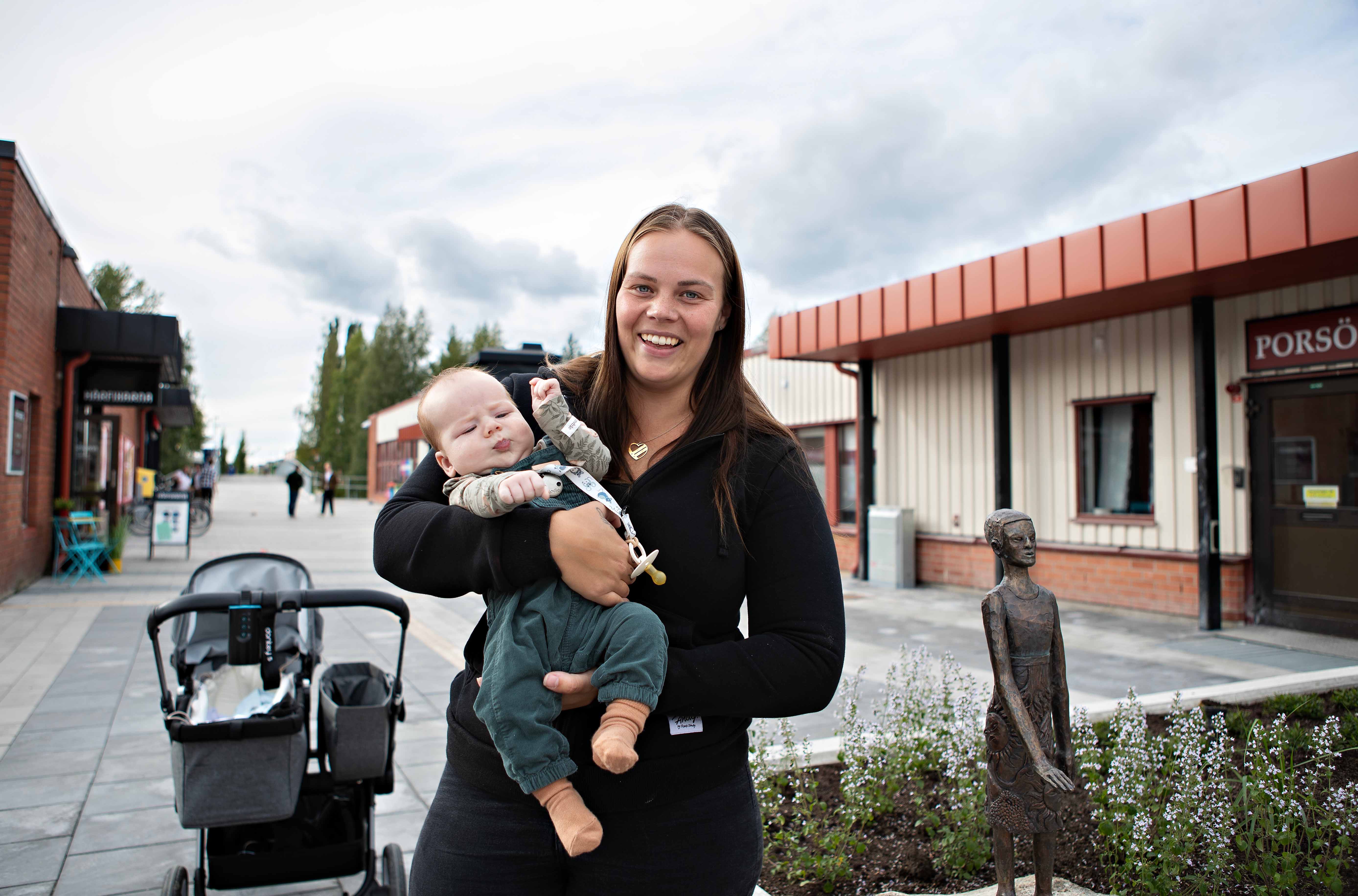 En leende kvinna håller sitt barn i famnen, i Porsö centrum.