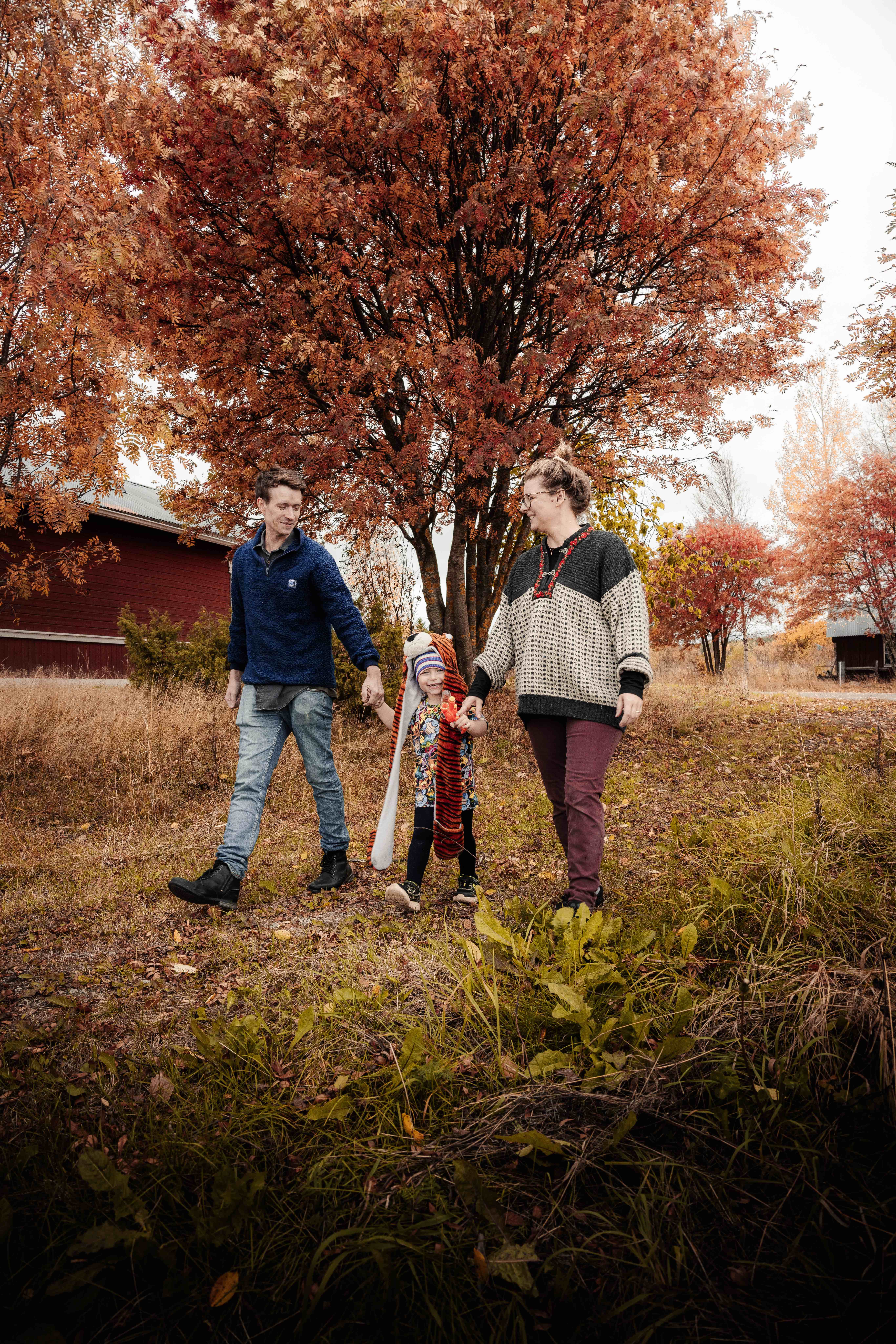 Sven, Karin och treåriga sonen går en promenad på den stora gården med orangefärgade höstlöv.