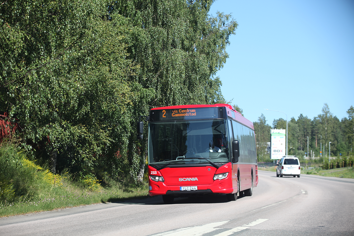 En röd LLT-buss kör på en bilväg.