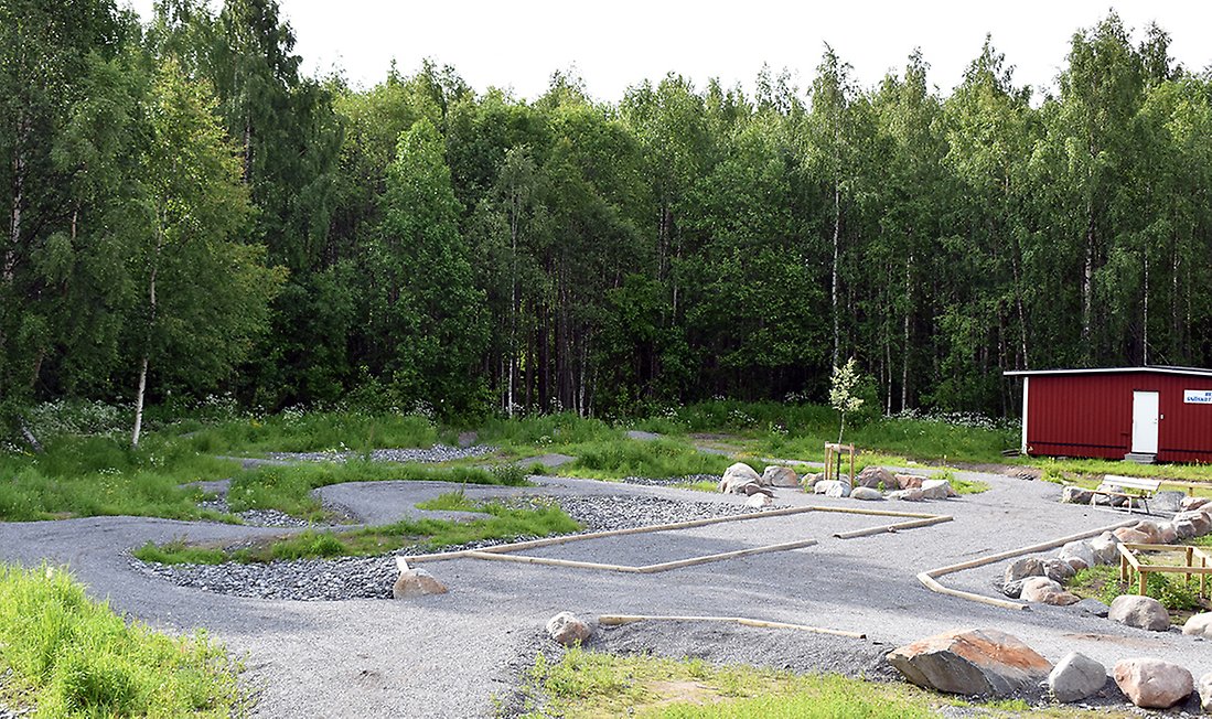 Boulebannan ligger på en plan grusplan med låga stockar som markerar spelytan. 