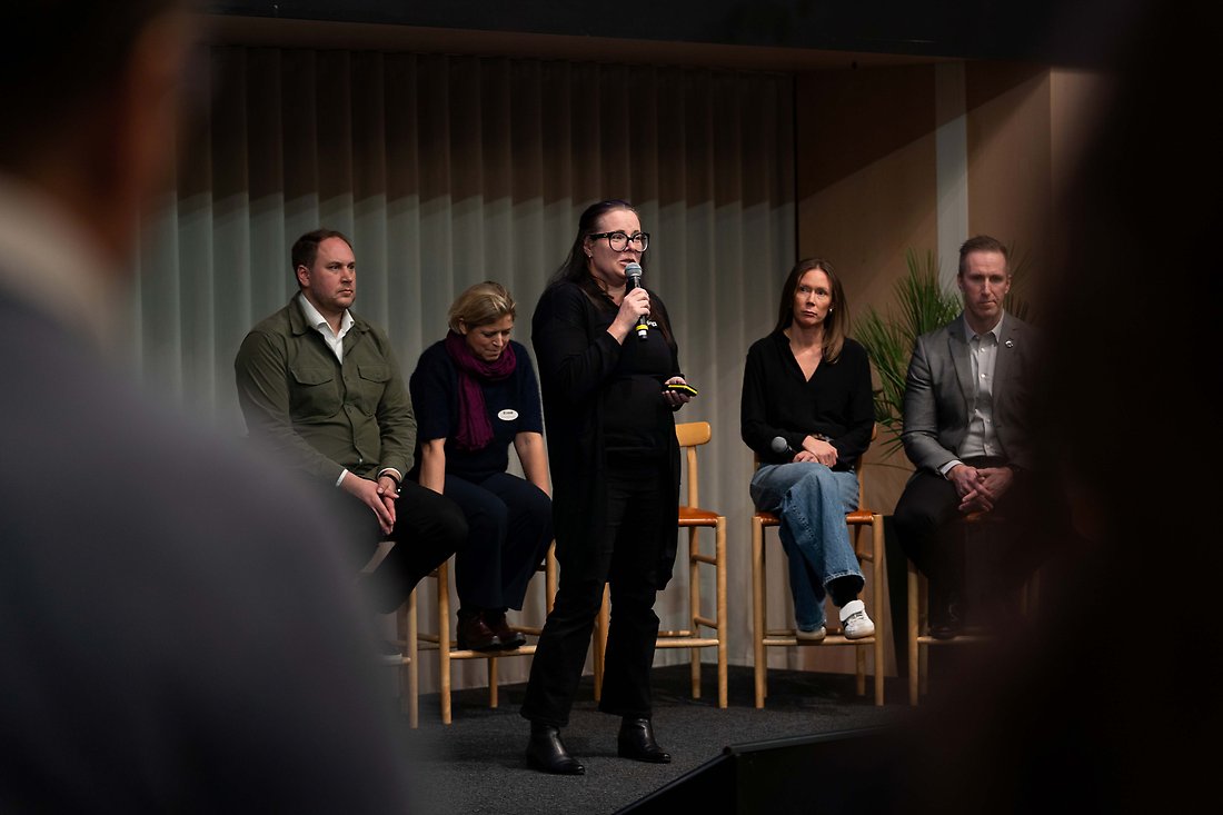 kvinna med mikrofon, flera personer bakom