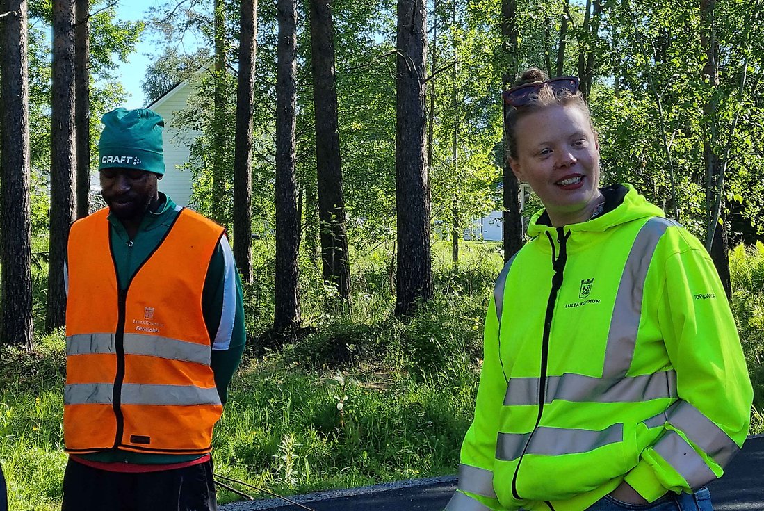 Ethany och Astrid står i skogen och berättar för ferieungdomarna om varför de ska bygga risormar och vad de gör för naturen.