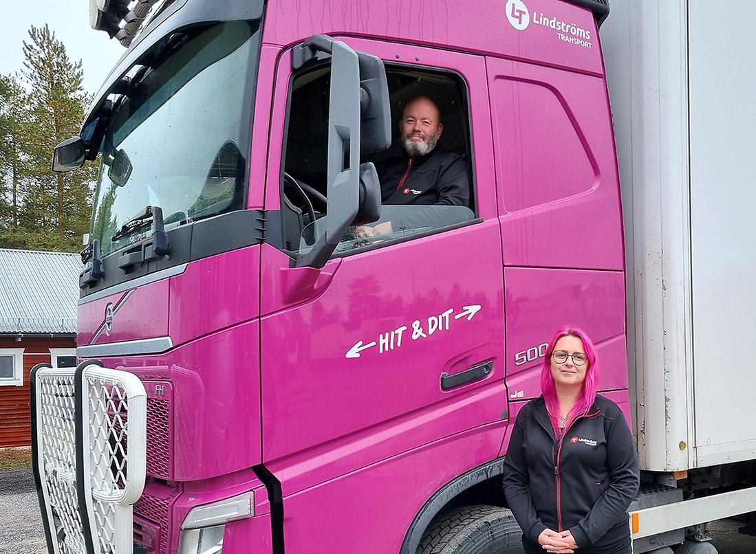 Man som sitter i en rosa lastbil. Kvinna med rosa hår står nedanför lastbilen.