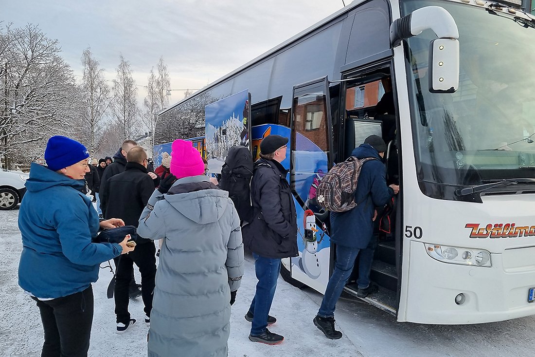 Människor som kliver på en buss. Det är snö på marken.