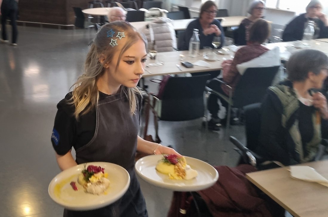Stella Fors serverar huvudrätten som är torsk med potatispuré och garnityr.