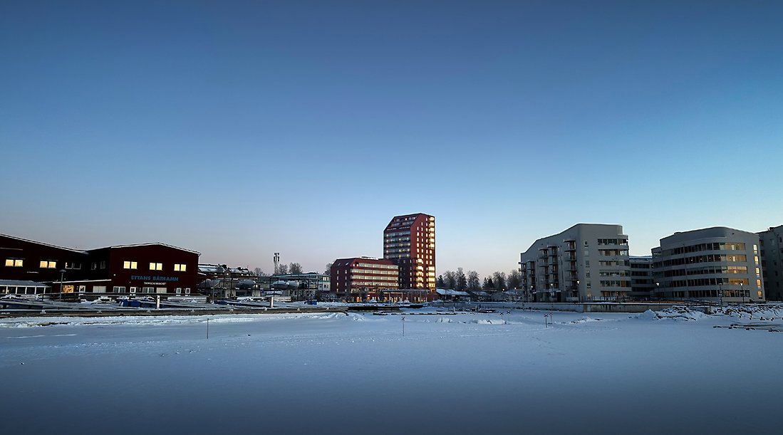 Vintervy över byggnad som detaljplanen möjliggör, med fasad i rödbrun plåt och trädetaljer.